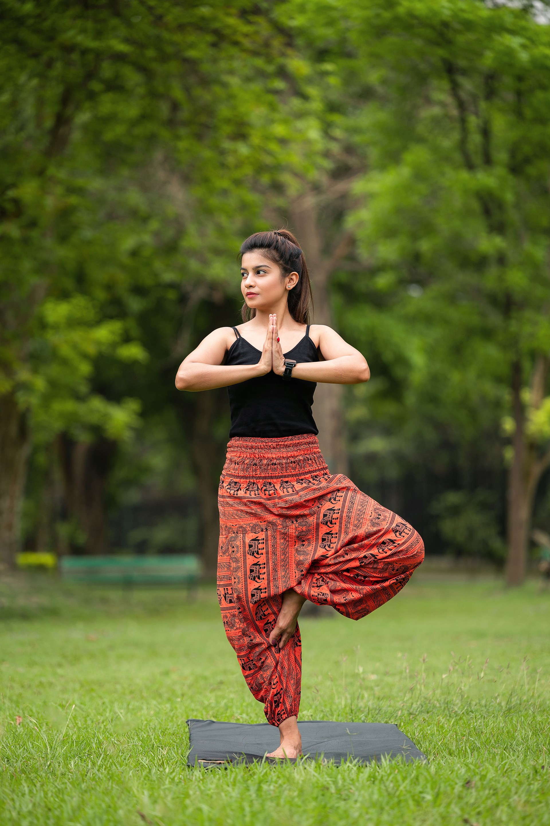 Vrikshasana or Tree Pose exercise. Athletic slim woman practicing yoga, standing on one leg in Namaste position.