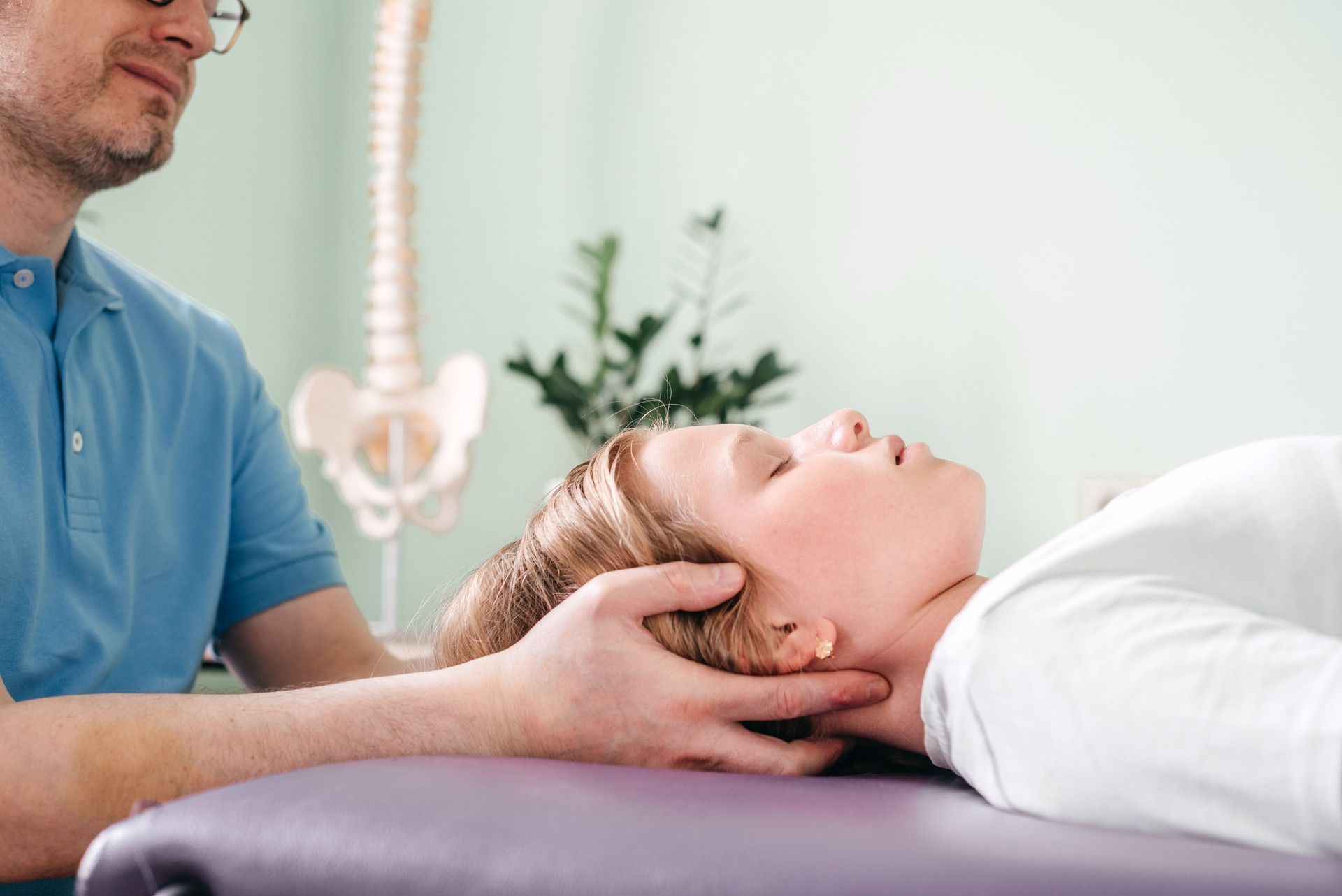 CST practitioner using light touch to provide craniosacral treatment to a girl patient, cranial sacral osteopathy